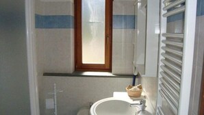A small bathroom with a toilet, sink, and window. - La Falconetta (Ayas)