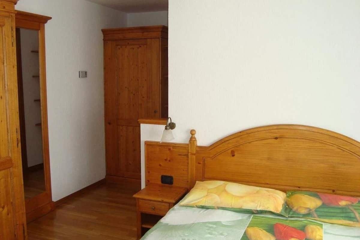 Un dormitorio con cama de madera, mesita de noche y armario.