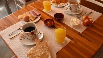 Una mesa de desayuno con cruasanes, jamón, huevos y diversas mermeladas.