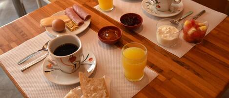 Uma mesa de café da manhã com croissants, presunto, ovos e diversas geleias.