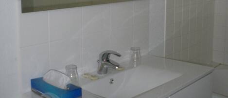 Un baño con un lavamanos blanco, un espejo y una caja de pañuelos azules.