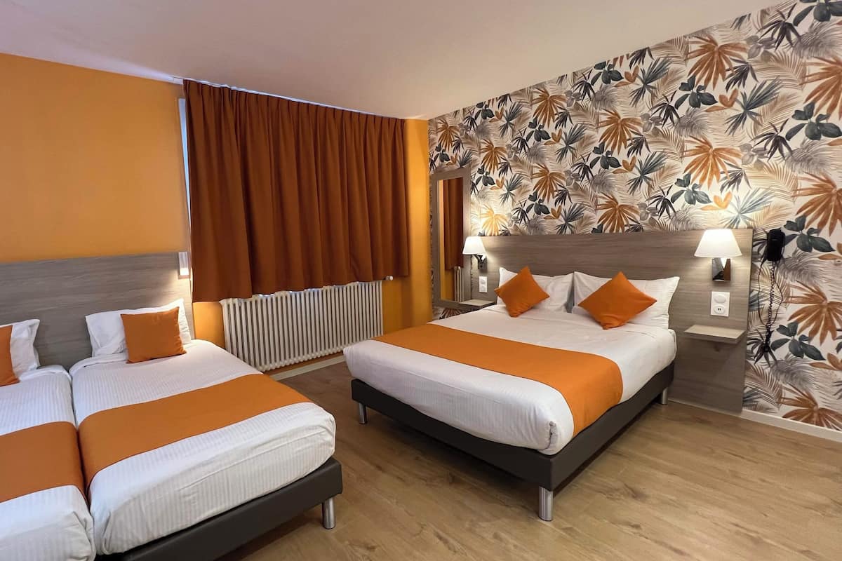 A hotel room with two beds, a radiator, a wall with a tropical leaf pattern, and a wooden floor.