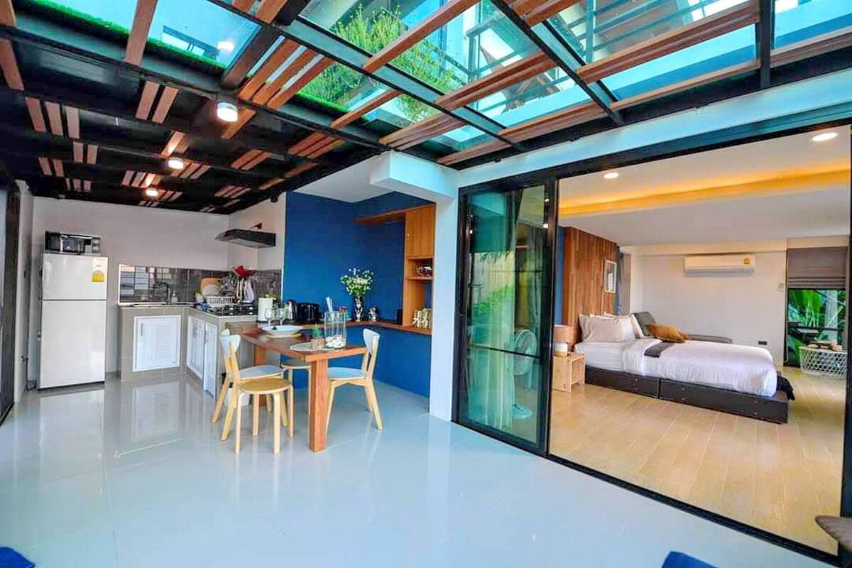 Um interior moderno com cozinha, área de refeições e um quarto com uma grande porta de vidro deslizante.