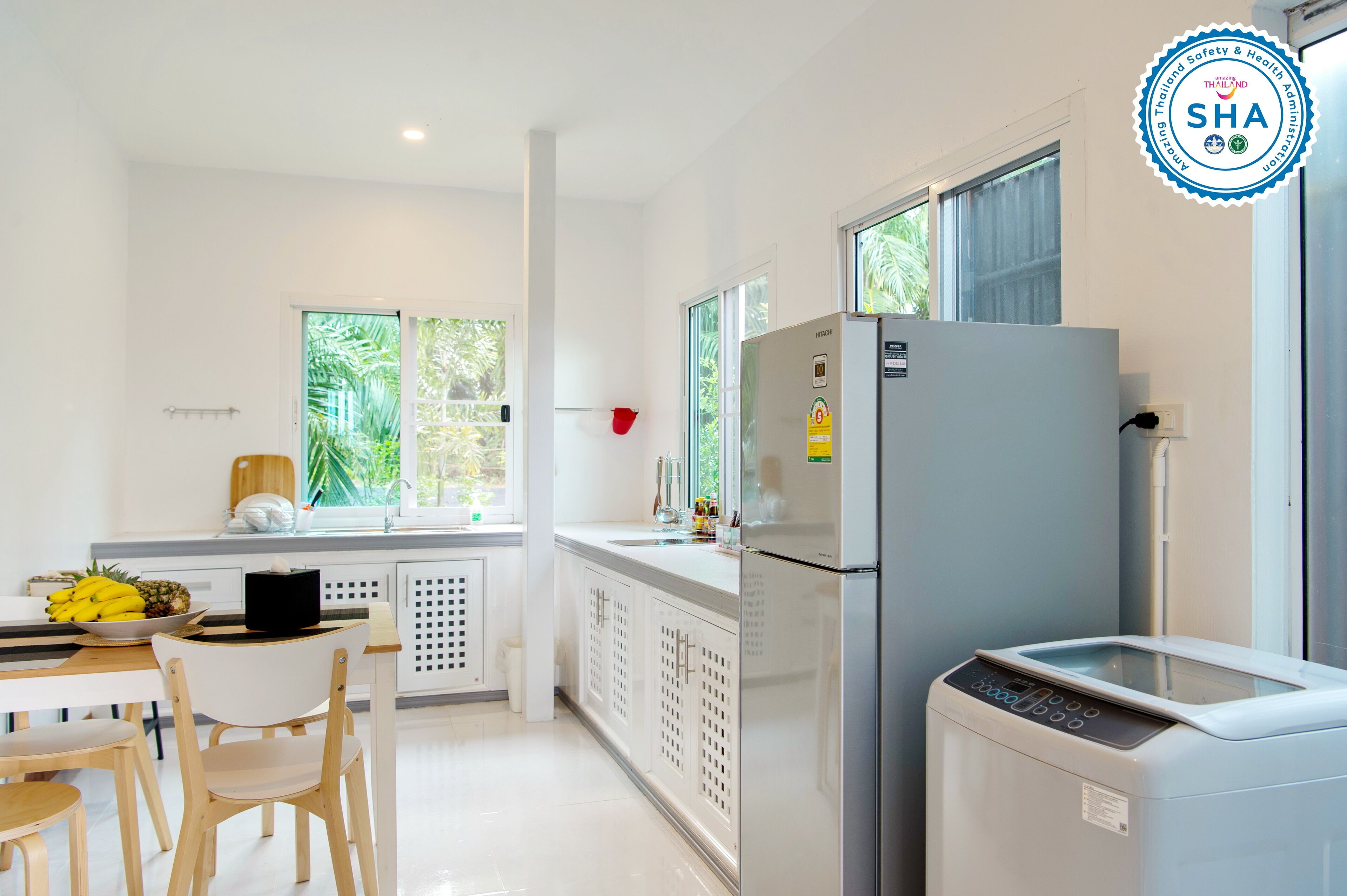 Una cucina moderna con frigorifero, microonde e lavello. Una finestra offre vista sul verde circostante.