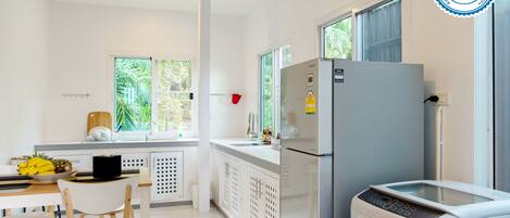 Una cucina moderna con frigorifero, microonde e lavello. Una finestra offre vista sul verde circostante.