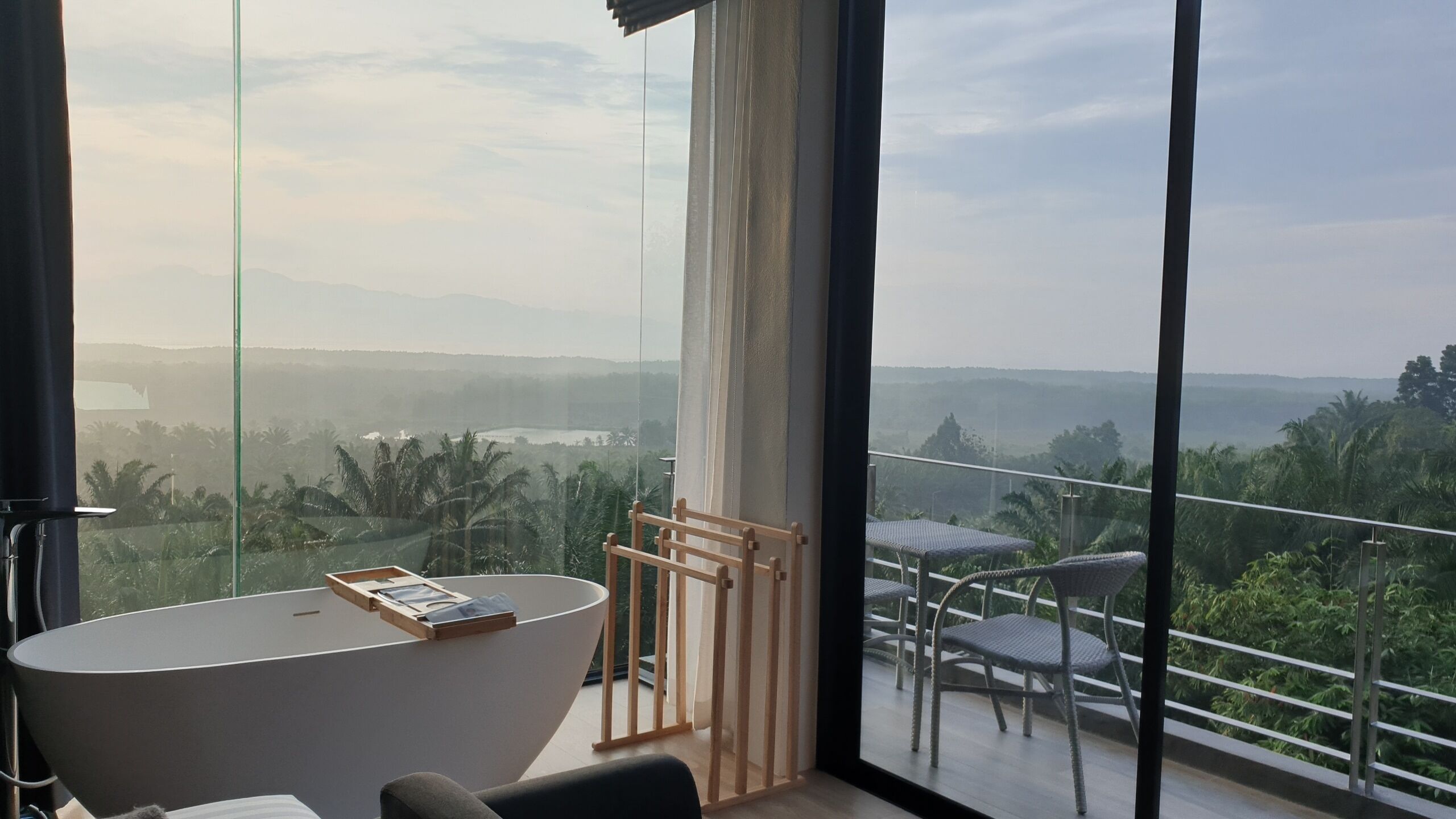 Una habitación moderna con un ventanal grande, una bañera y un comedor con sillas.