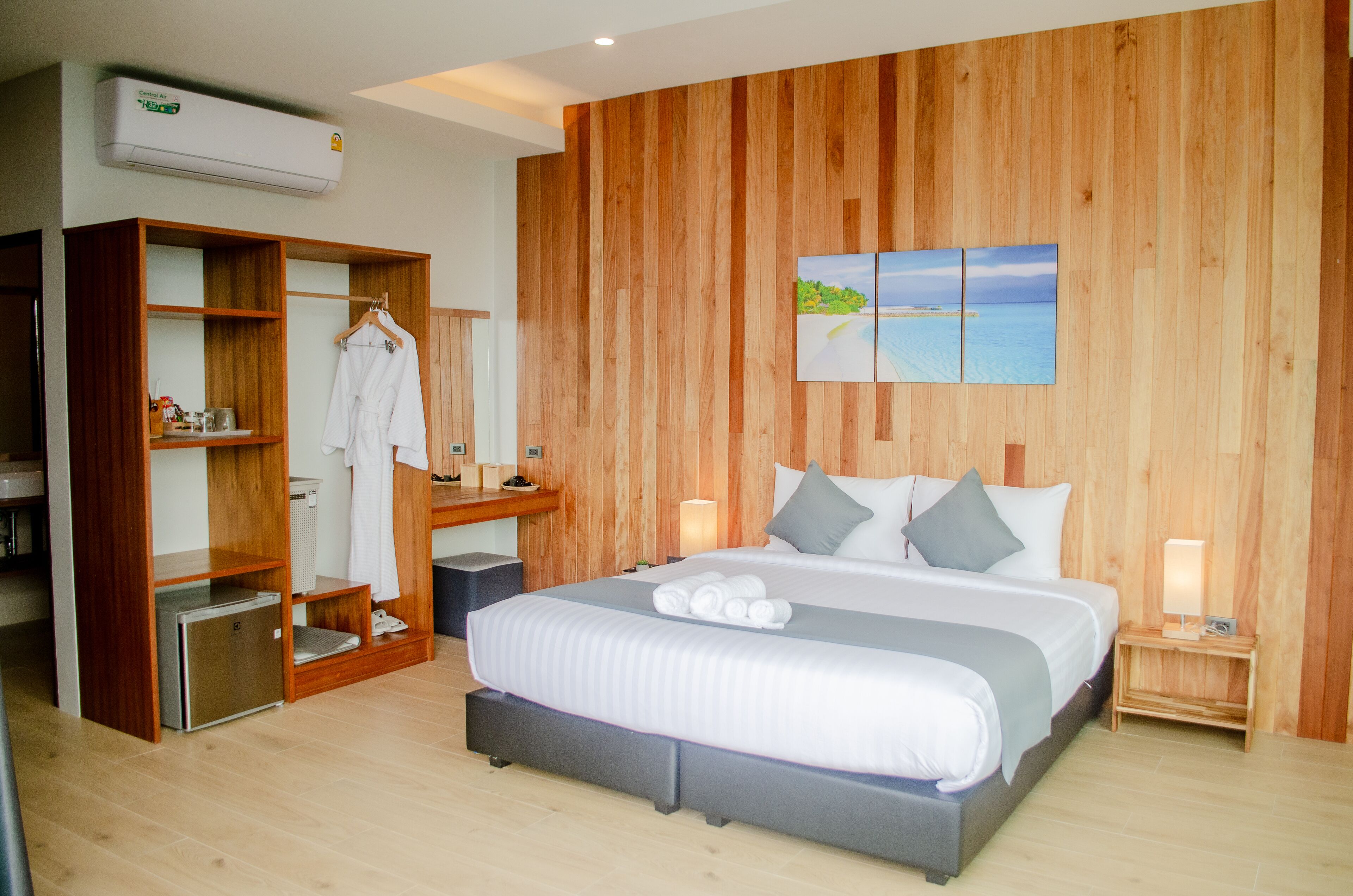 A modern bedroom with a wooden wall, a bed with grey bedding, a bedside table with a lamp, and a wooden wardrobe with a mirror.