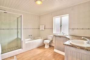 Un baño con ducha de vidrio, bañera, inodoro y lavamanos.