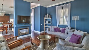 A living room with a TV, sofa, coffee table, and a fireplace. - Maudville (Cape Town)