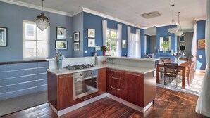 A modern kitchen with wooden cabinets, stainless steel appliances, and a dining area with a wooden table and chairs. - Maudville (Cape Town)