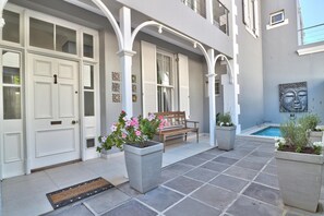 A courtyard with a white door, a bench, and potted plants.