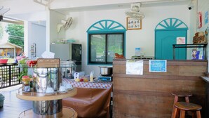 A kitchen area with a table set for dining, a refrigerator, and various kitchen appliances. - Kodtalay Resort (Tha Mai)