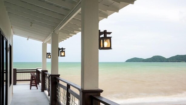 A covered balcony with a view of a beach and distant hills. - Kodtalay Resort (Tha Mai)