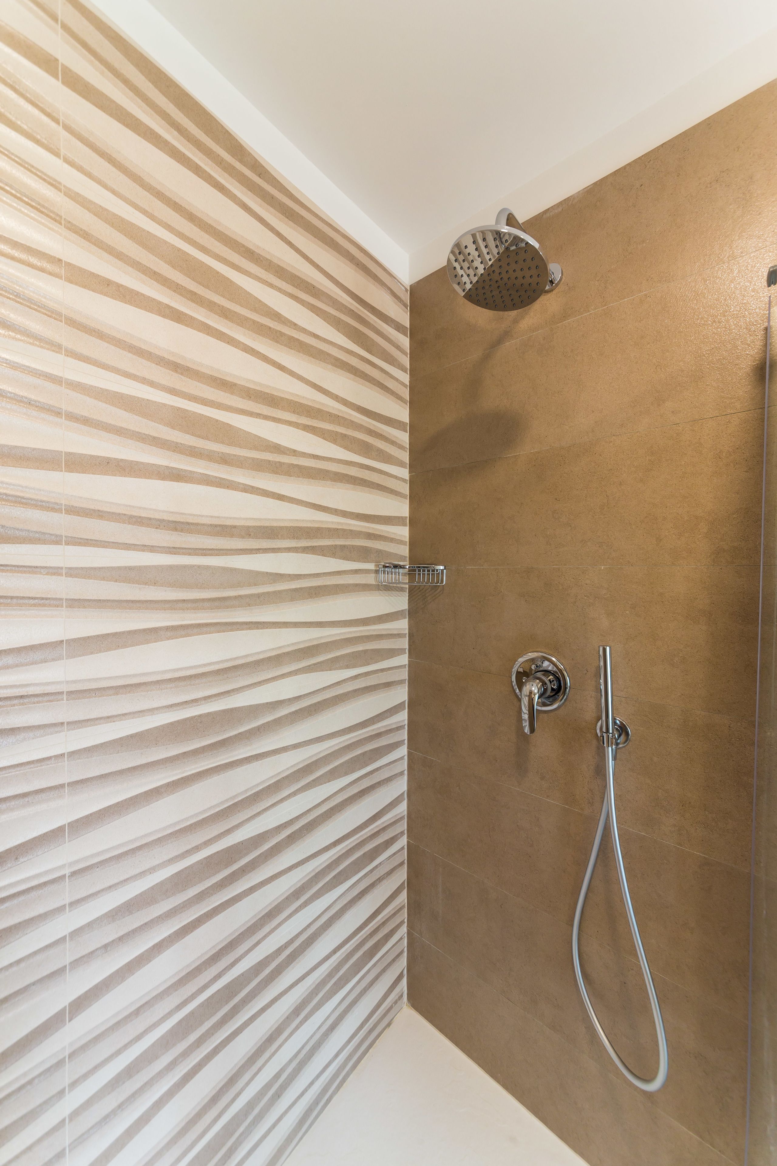 Un baño moderno con ducha, un perchero y una pared con un diseño ondulado.