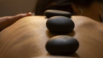 A close-up of a massage table with three black stones placed on it.