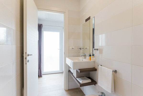A modern bathroom with a white sink, mirror, and tiled walls. - Torre Cintola Greenblu Sea Emotions (Monopoli)