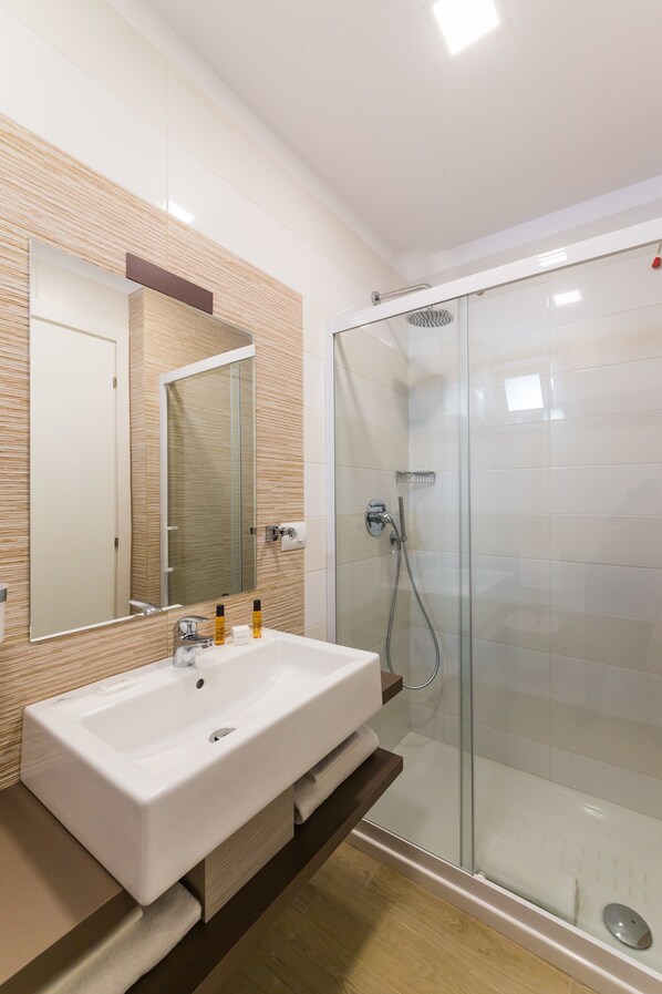 A modern bathroom with a large sink, mirror, and glass shower enclosure.