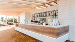 A modern bar area with a wooden floor, white counter, and various bar equipment.