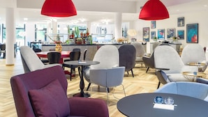 A modern hotel lobby with seating areas, a reception desk, and artwork on the walls. - Holiday Inn - the niu, Franz Vienna by IHG (Vienna)