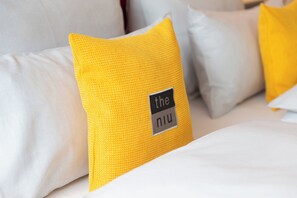 Un lit avec un oreiller jaune et une étiquette sur laquelle on peut lire « the niu ».
