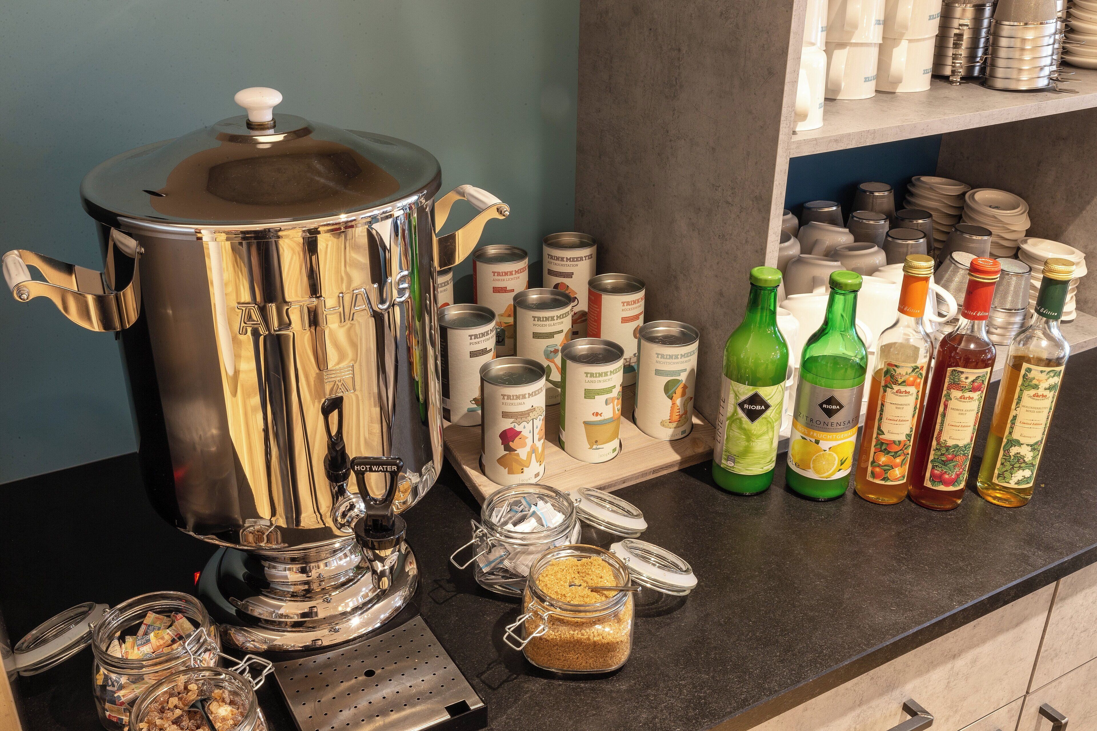 A kitchen counter with a large stainless steel pot, several glass jars, and a variety of canned goods and bottles.