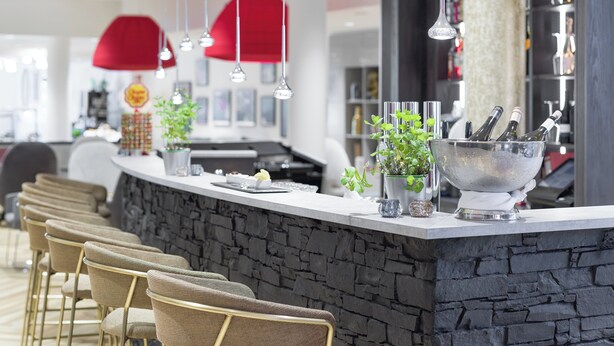 A modern bar area with a stone counter, hanging pendant lights, and bar stools. - Holiday Inn - the niu, Franz Vienna by IHG (Vienna)