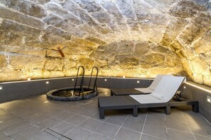 A stone-walled sauna with two lounge chairs and a circular hot tub. - Hotell Järvsöbaden (Jarvso)