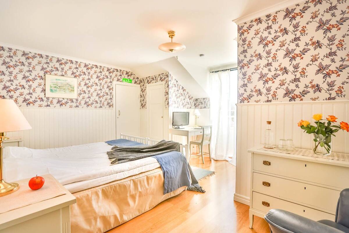 A bedroom with a bed, a desk, a chair, and a dresser.
