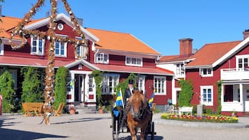 A red building with a traditional design, a horse-drawn carriage, and Swedish flags.