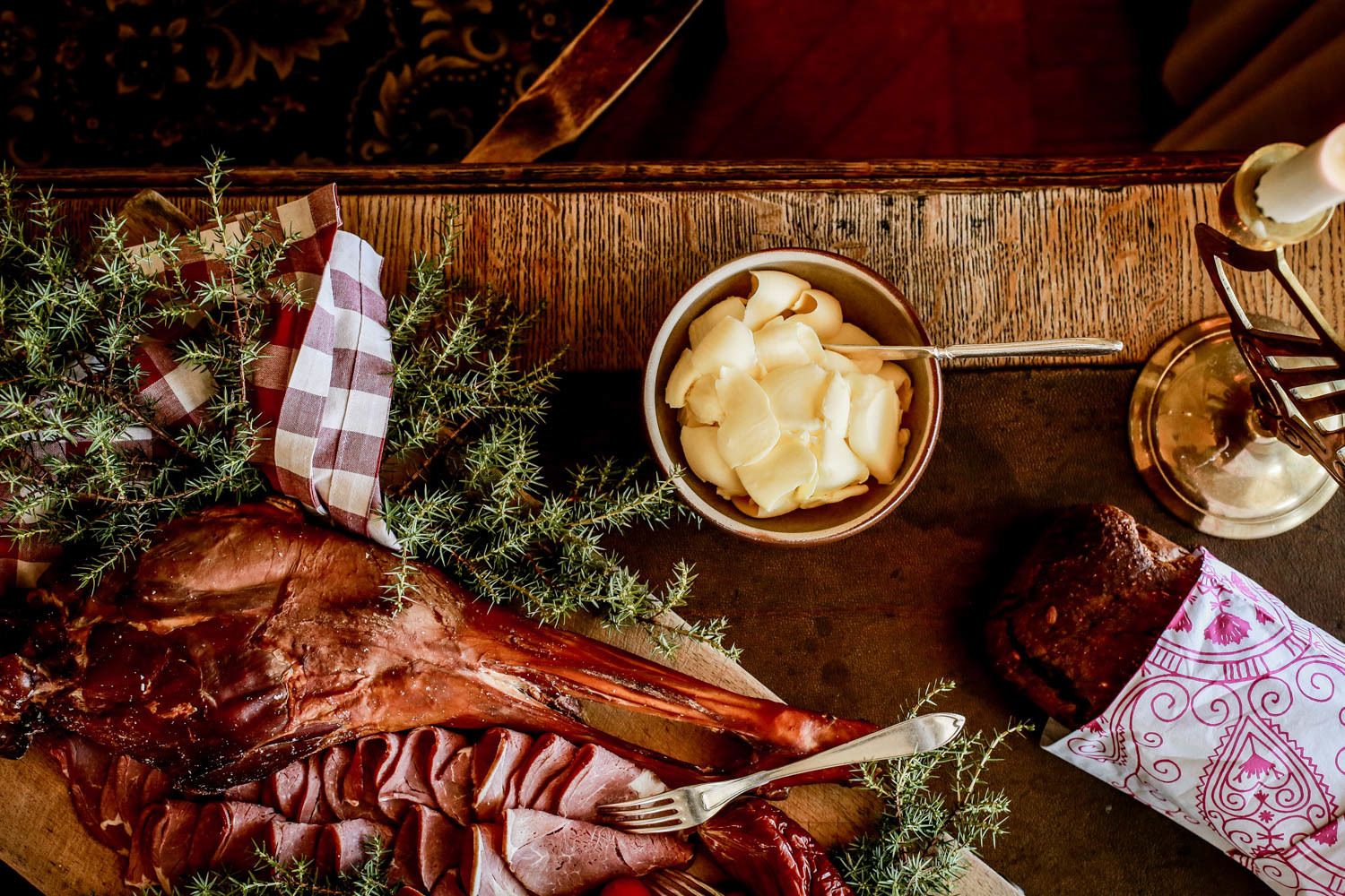 Una mesa de madera con un cordero asado, un bol de manzanas en rodajas y una botella de miel.