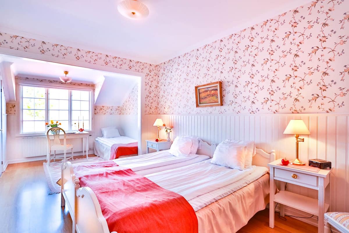 A bedroom with a large bed, two bedside tables, a chair, and a window with a view.