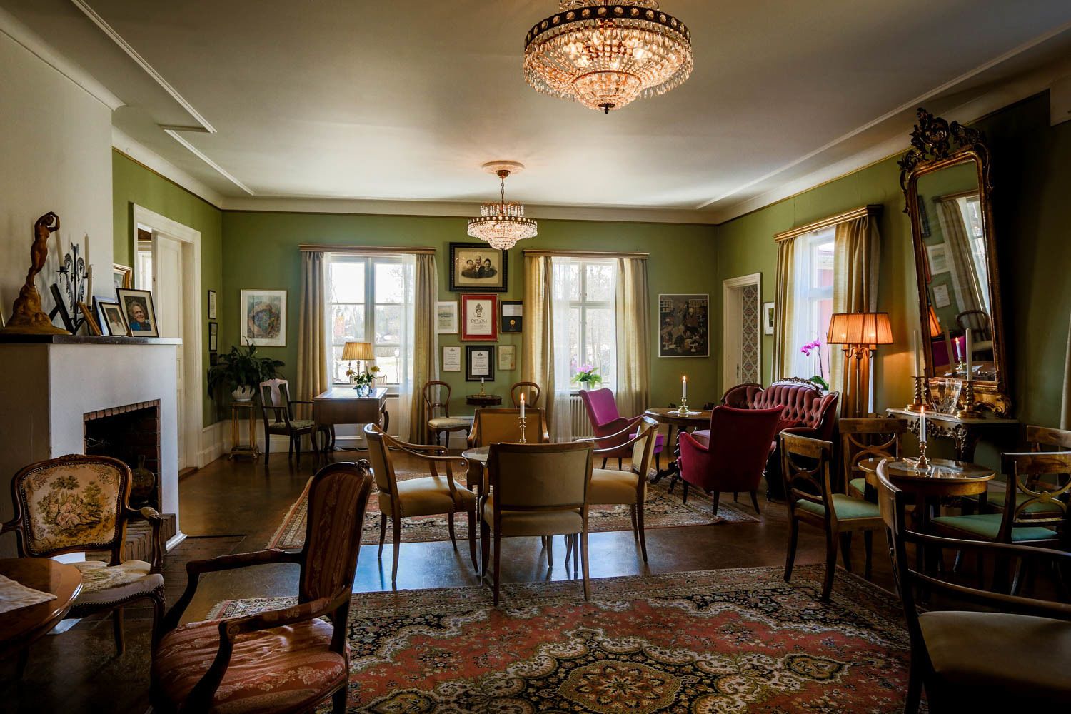 Une pièce de style traditionnel, dotée d’une cheminée, d’un lustre et d’un coin repas avec des chaises et une table.