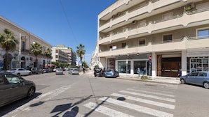 Straßenansicht mit Zebrastreifen, Autos und Gebäuden.