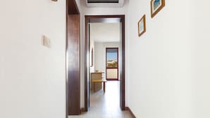 Un couloir avec une porte en bois qui donne sur une pièce dotée d’une fenêtre.