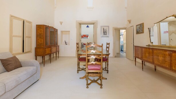 A spacious room with a dining table and chairs, a sofa, and a wooden cabinet. - Appartamento Turrita (Presicce-Acquarica)
