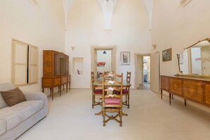 A spacious room with a dining table and chairs, a sofa, and a wooden cabinet. - Appartamento Turrita (Presicce-Acquarica)