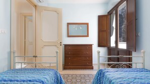 A bedroom with two beds, a dresser, and a door leading to another room. - Appartamento Turrita (Presicce-Acquarica)