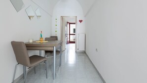 A dining area with a table and chairs, a white wall with mirrors, and a hallway leading to another room. - Casa Angiulina (San Pancrazio Salentino)