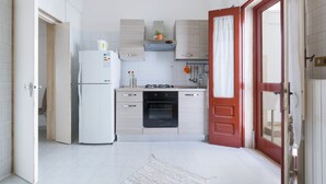 A compact kitchen with a refrigerator, oven, and sink. - Casa Angiulina (San Pancrazio Salentino)