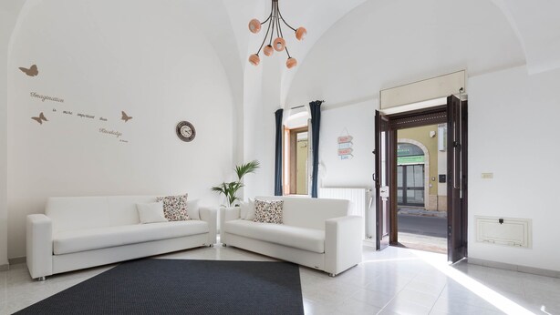A modern living room with a white sofa, a black rug, and a ceiling light fixture. - Casa Angiulina (San Pancrazio Salentino)