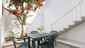 A patio with a table and chairs, a small tree with red flowers, and a staircase. - Casa Angiulina (San Pancrazio Salentino)