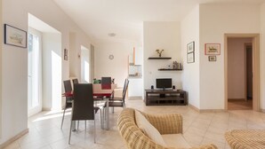 A spacious living area with a dining table, chairs, a sofa, and a TV. - Casa di Pietro (Nardò)