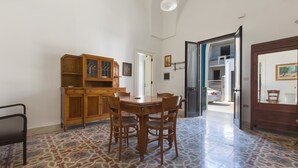 A dining area with a wooden table and chairs, a cabinet, and patterned floor tiles. - Casa Graziella (Neviano)