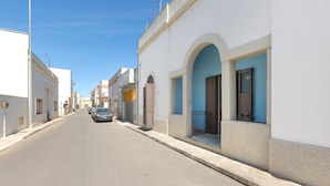 A street with white buildings, some with blue doors and windows. - Casa Graziella (Neviano)