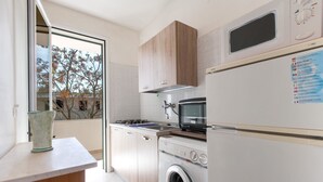 A modern kitchen with a built-in washing machine, a microwave, and a stove. - Casetta del Glicine (Melendugno)