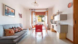 Un salon moderne comprenant un canapé, une table à manger et des chaises. Il y a également un coin cuisine avec des placards et un four à micro-ondes.