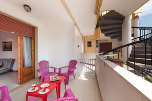 Ein Balkon mit Essbereich, Stühlen und einer Treppe.