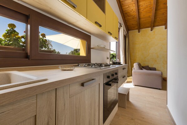 Una cocina moderna con armarios de madera, una estufa a gas y un amplio ventanal con vistas al jardín.