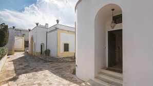 Una estrecha calle adoquinada bordeada por edificios blancos con puertas arqueadas y pequeñas ventanas.
