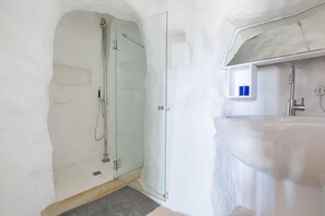 A modern bathroom with a glass-enclosed shower, a white sink, and a small shelf with a blue object. - Il Giardino delle Cipolliane (Gagliano del Capo)